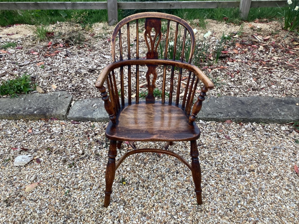 A dark brown Georgian Windsor armchair featuring a curved back rail, central pierced splat, turned spindles, shaped armrests, a solid saddle seat, and turned wooden legs. View II