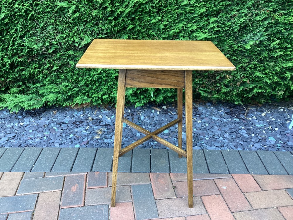 A rectangular solid oak Arts and Crafts side table featuring splayed tapered legs and an X-frame lower stretcher.