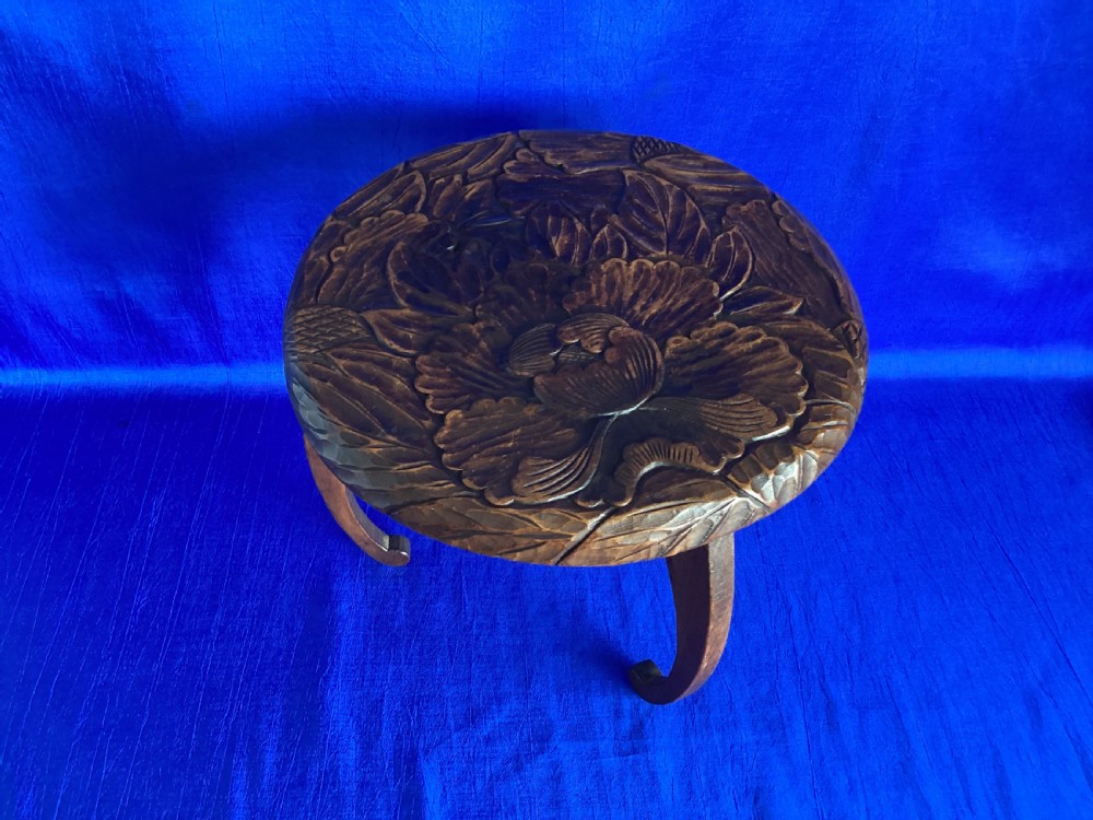 A low circular wooden plant stand featuring hand-carved floral motifs on the surface and curved legs. View IX