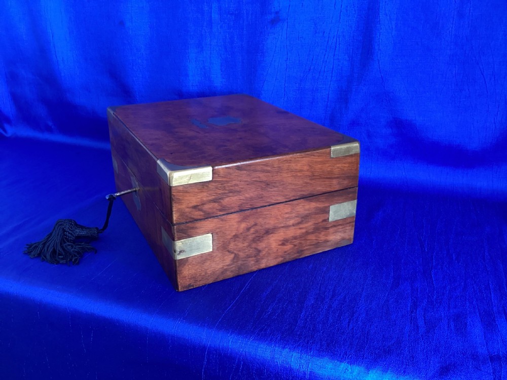 A rectangular Victorian walnut wooden box featuring protective brass corner brackets, a central keyhole escutcheon plate, and an inlaid lid cartouche. View II