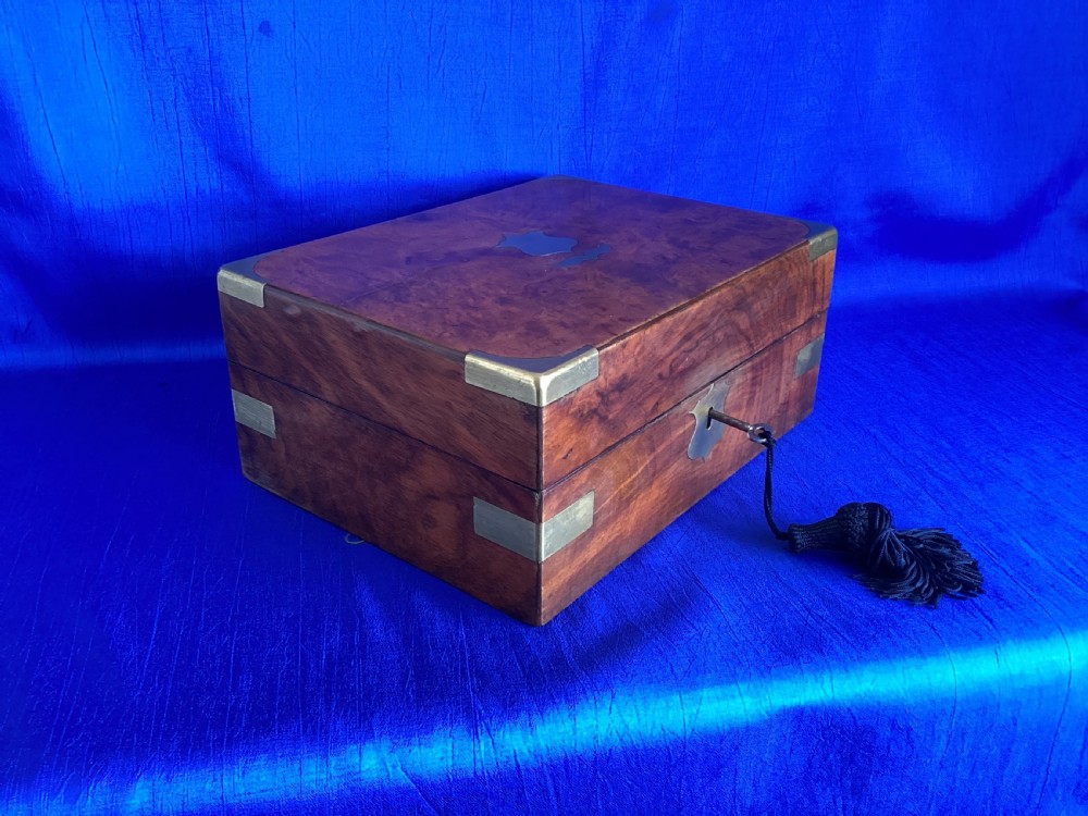 A rectangular Victorian walnut wooden box featuring protective brass corner brackets, a central keyhole escutcheon plate, and an inlaid lid cartouche. View III