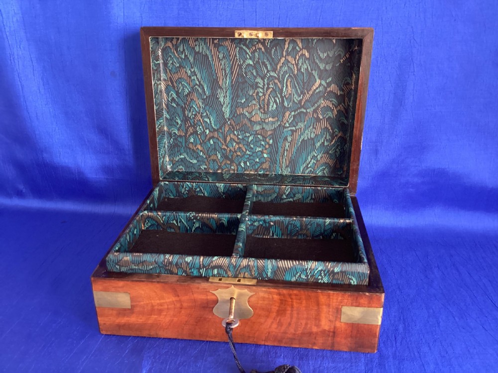 A rectangular Victorian walnut wooden box featuring protective brass corner brackets, a central keyhole escutcheon plate, and an inlaid lid cartouche. View IV