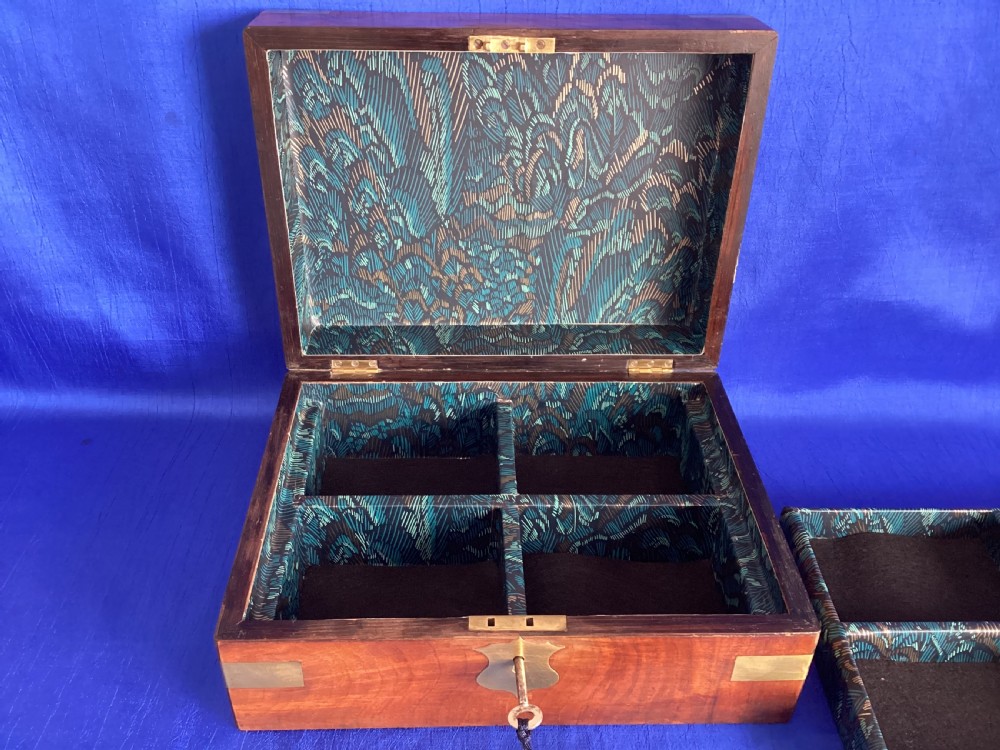 A rectangular Victorian walnut wooden box featuring protective brass corner brackets, a central keyhole escutcheon plate, and an inlaid lid cartouche. View V