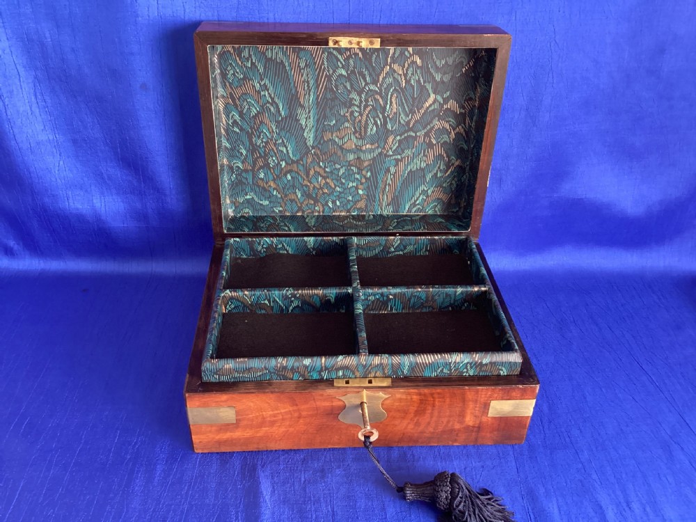 A rectangular Victorian walnut wooden box featuring protective brass corner brackets, a central keyhole escutcheon plate, and an inlaid lid cartouche. View VI