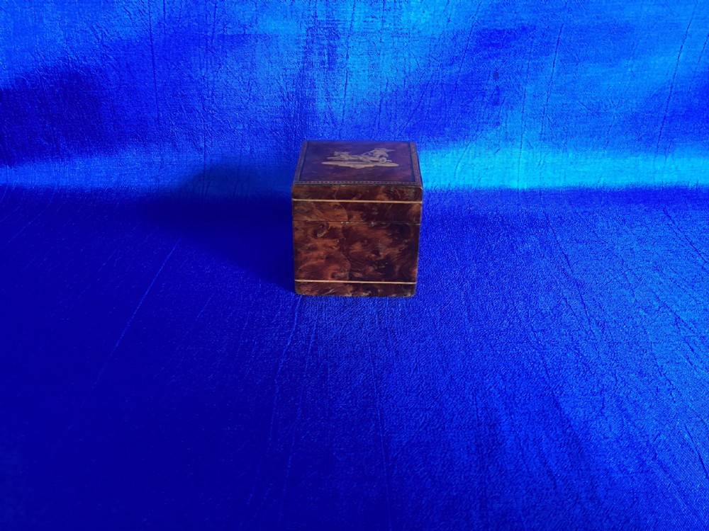 A small square Victorian burr walnut travelling inkwell box featuring detailed mosaic wood inlay on the lid.