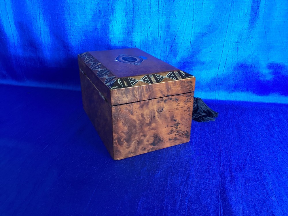 A rectangular Georgian burr walnut tea caddy featuring geometric inlaid borders on the lid and a key with a black tassel. View III