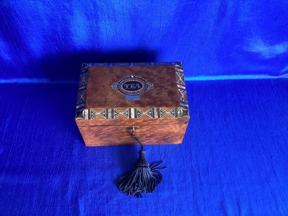A rectangular Georgian burr walnut tea caddy featuring geometric inlaid borders on the lid and a key with a black tassel. View V