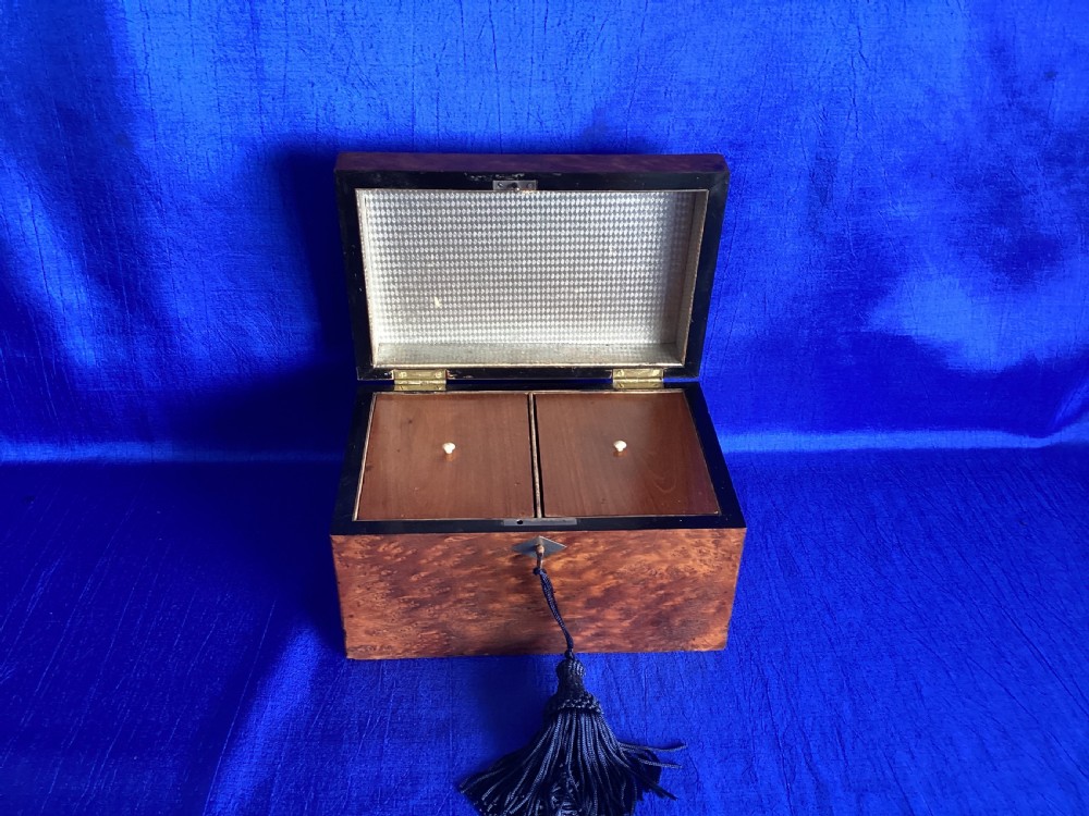 A rectangular Georgian burr walnut tea caddy featuring geometric inlaid borders on the lid and a key with a black tassel. View VI