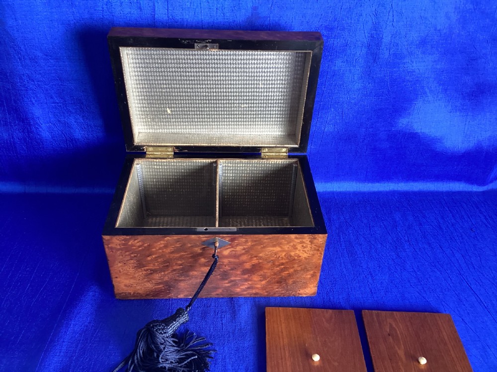 A rectangular Georgian burr walnut tea caddy featuring geometric inlaid borders on the lid and a key with a black tassel. View VII
