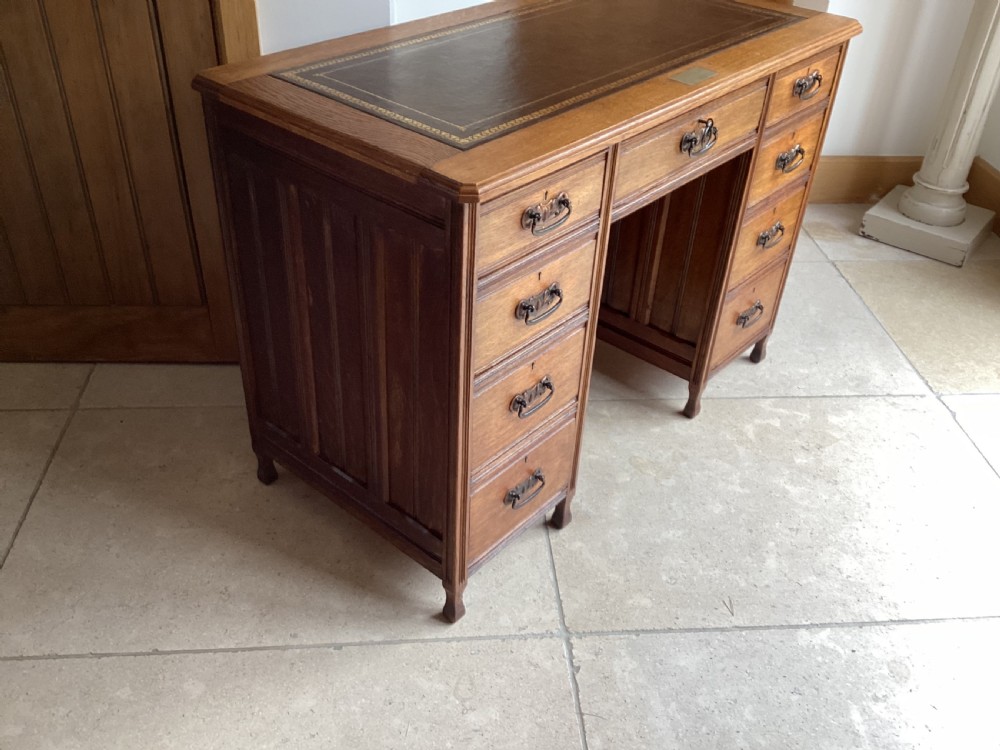 An Edwardian oak twin pedestal desk with nine drawers featuring brass handles and a leather writing surface insert. View IV