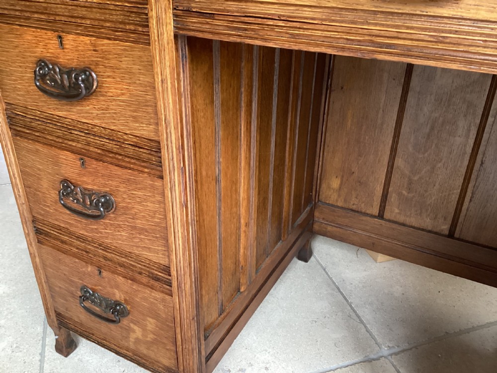 An Edwardian oak twin pedestal desk with nine drawers featuring brass handles and a leather writing surface insert. View VI