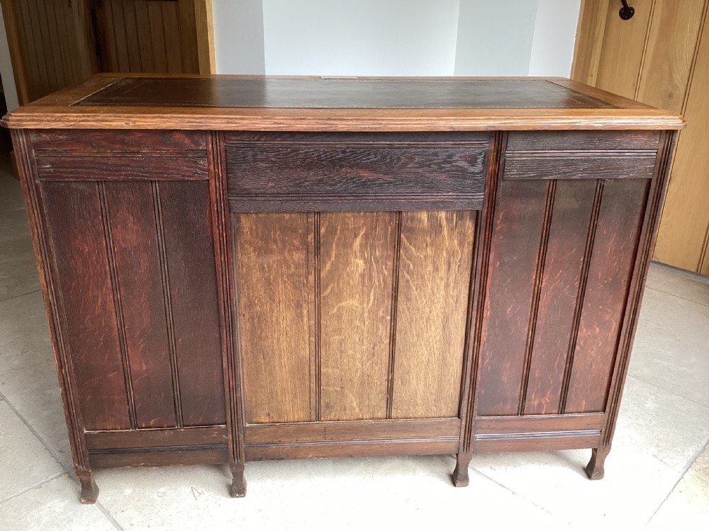 An Edwardian oak twin pedestal desk with nine drawers featuring brass handles and a leather writing surface insert. View IX