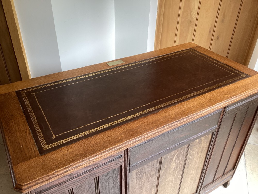 An Edwardian oak twin pedestal desk with nine drawers featuring brass handles and a leather writing surface insert. View XI