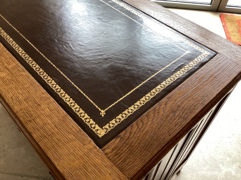 An Edwardian oak twin pedestal desk with nine drawers featuring brass handles and a leather writing surface insert. View XII