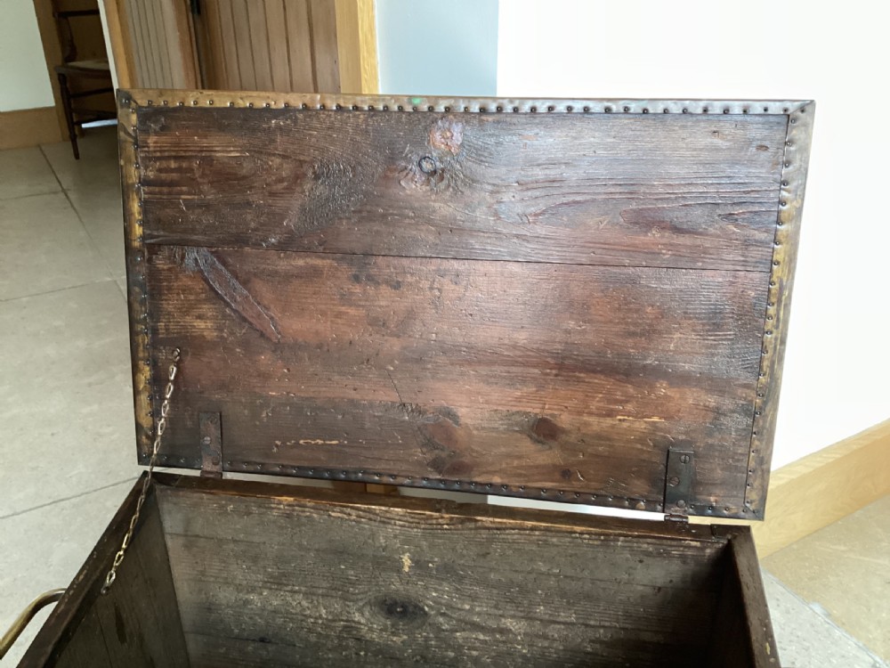 An antique brass-clad wooden fireside log box featuring embossed relief scenes of figures in a tavern on the front and foliate scrollwork on the lid. View VIII