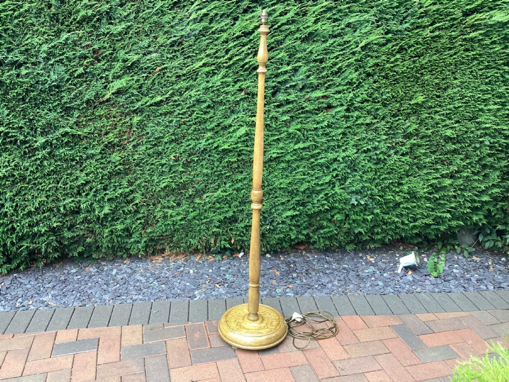 An Edwardian turned oak standard lamp featuring a tapered central column and a stepped circular base.