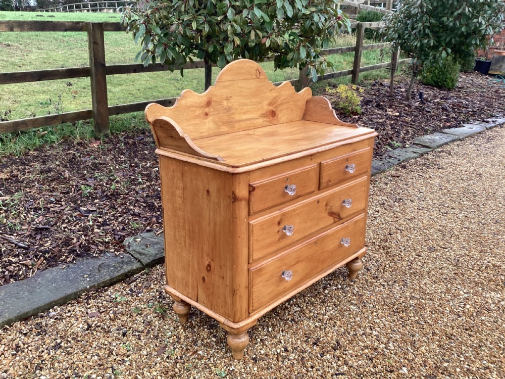 A Victorian honey pine chest of drawers featuring a shaped gallery upstand, clear glass knobs, and turned feet. View II