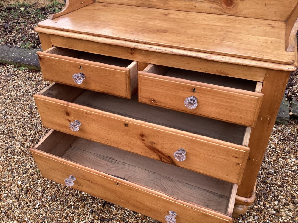 A Victorian honey pine chest of drawers featuring a shaped gallery upstand, clear glass knobs, and turned feet. View III