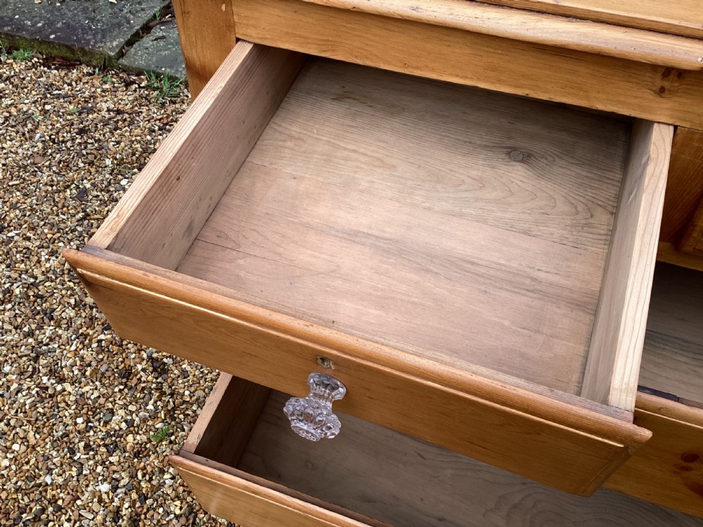 A Victorian honey pine chest of drawers featuring a shaped gallery upstand, clear glass knobs, and turned feet. View V