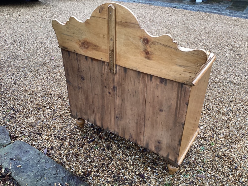 A Victorian honey pine chest of drawers featuring a shaped gallery upstand, clear glass knobs, and turned feet. View VII