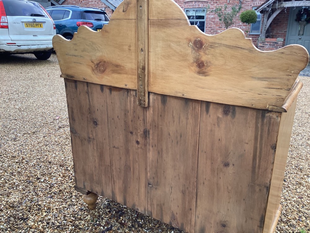 A Victorian honey pine chest of drawers featuring a shaped gallery upstand, clear glass knobs, and turned feet. View VIII