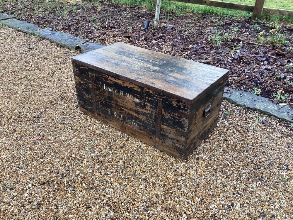 A rectangular antique dark wood military campaign chest featuring stencilled white lettering and iron strap reinforcements. View II