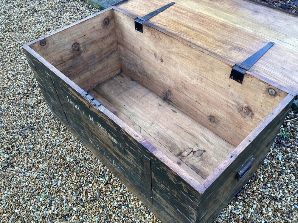 A rectangular antique dark wood military campaign chest featuring stencilled white lettering and iron strap reinforcements. View V