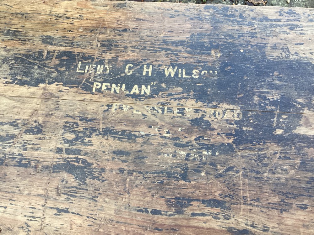 A rectangular antique dark wood military campaign chest featuring stencilled white lettering and iron strap reinforcements. View VI