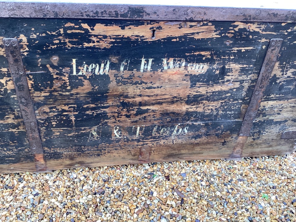 A rectangular antique dark wood military campaign chest featuring stencilled white lettering and iron strap reinforcements. View VII