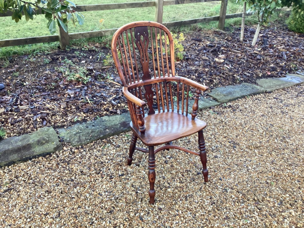A wooden Georgian Windsor armchair featuring a hoop back, central pierced splat, vertical spindles, shaped seat, turned legs, and curved armrests. View II