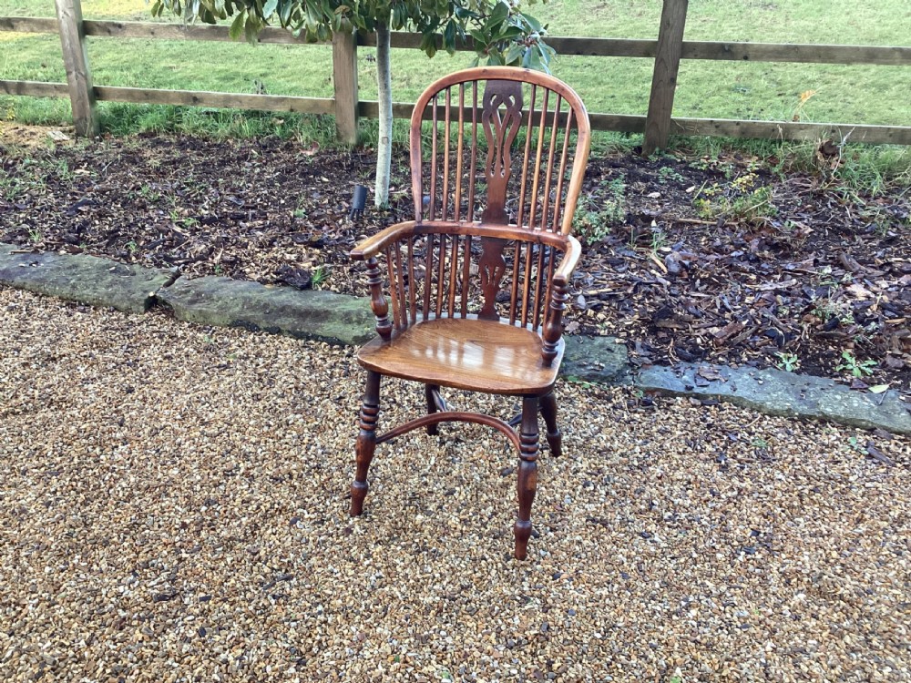 A wooden Georgian Windsor armchair featuring a hoop back, central pierced splat, vertical spindles, shaped seat, turned legs, and curved armrests. View III