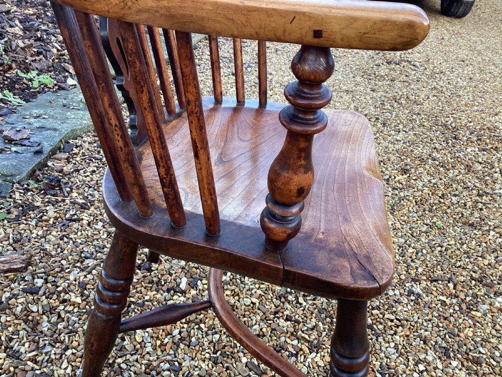 A wooden Georgian Windsor armchair featuring a hoop back, central pierced splat, vertical spindles, shaped seat, turned legs, and curved armrests. View V