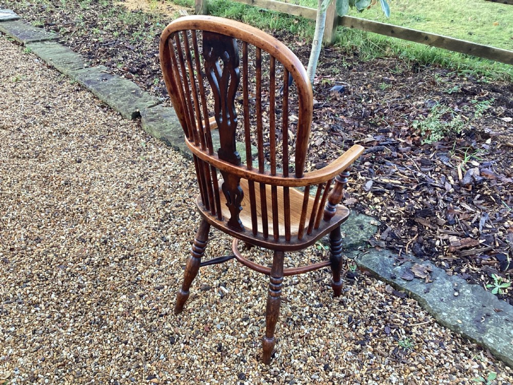 A wooden Georgian Windsor armchair featuring a hoop back, central pierced splat, vertical spindles, shaped seat, turned legs, and curved armrests. View VII