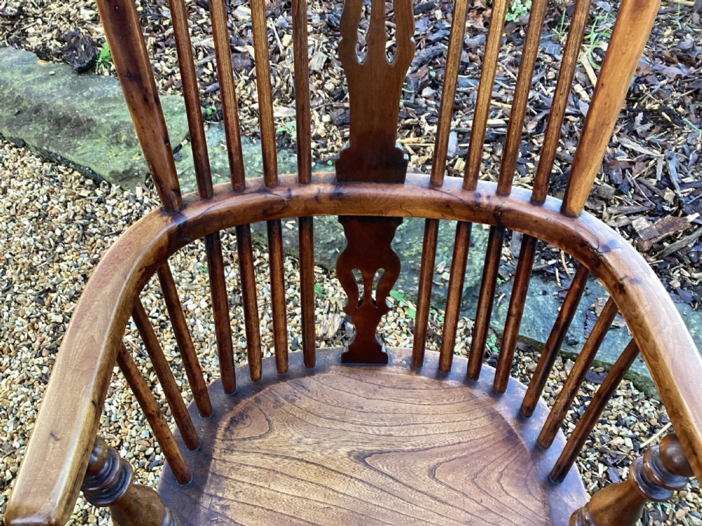 A wooden Georgian Windsor armchair featuring a hoop back, central pierced splat, vertical spindles, shaped seat, turned legs, and curved armrests. View IX