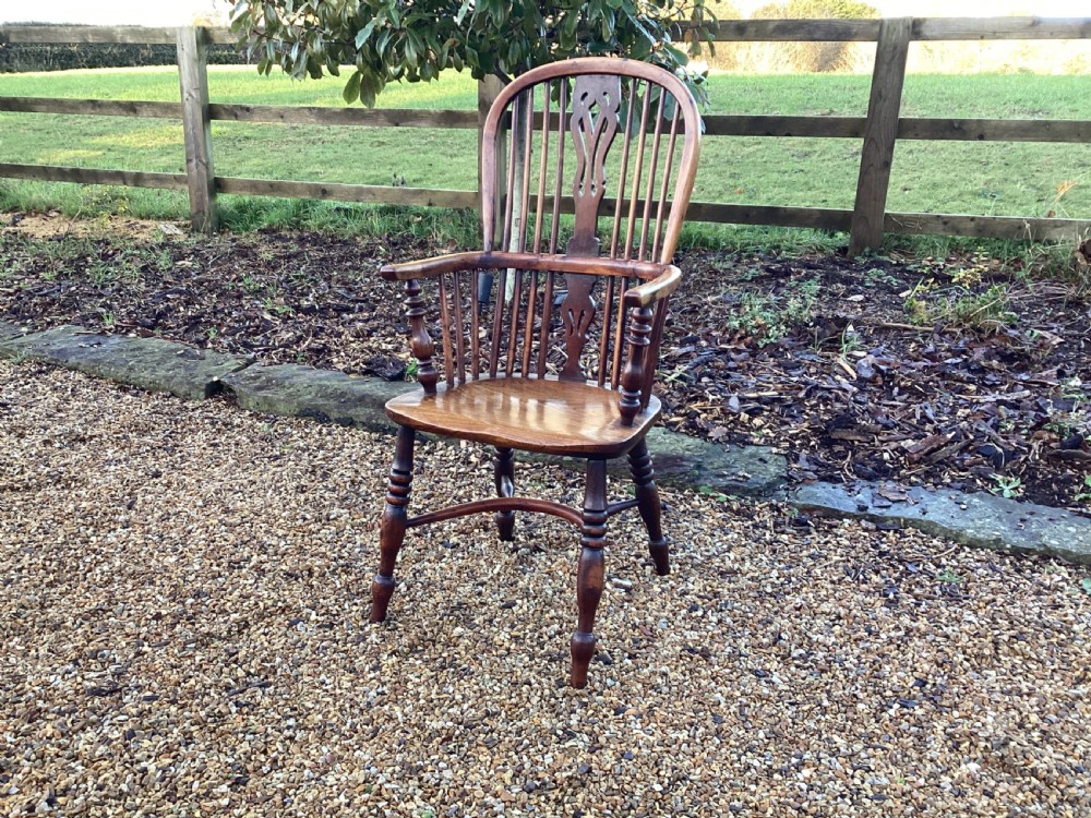 A wooden Georgian Windsor armchair featuring a hoop back, central pierced splat, vertical spindles, shaped seat, turned legs, and curved armrests. View X