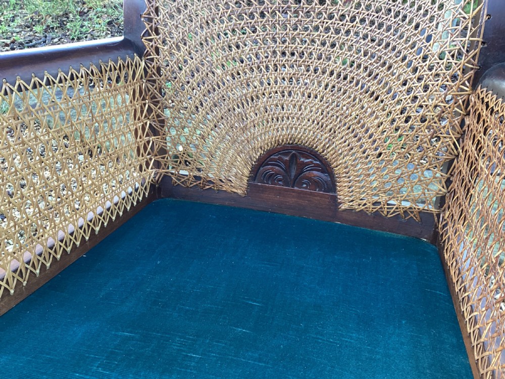 A dark mahogany Art Deco bergere armchair featuring fan pattern cane backrest weaving, cane side panels, cabriole legs, and a rich teal velvet seat cushion. View IX