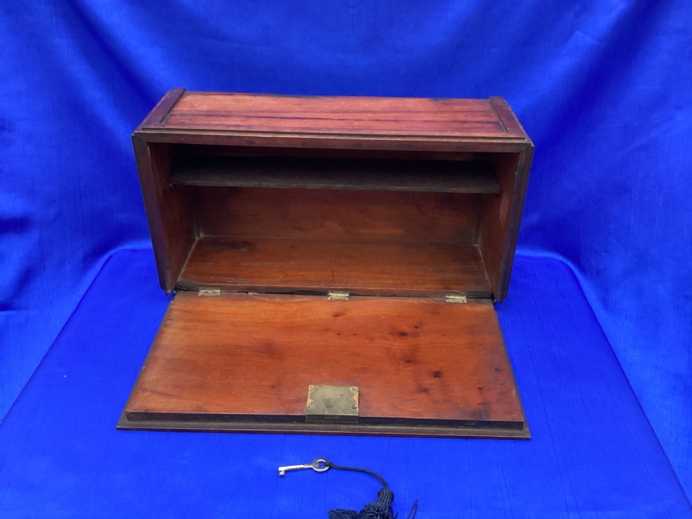 A rectangular mahogany table cabinet with carved Gothic blind tracery along the front face and a central keyhole with a black tassel attached. View V