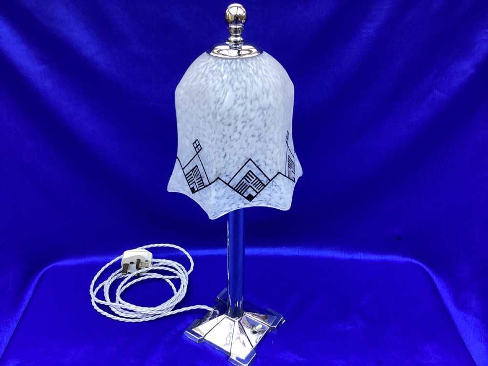 An Art Deco chrome table lamp featuring a central column stem, stepped square base, and a mottled frosted glass bell shade decorated with black geometric diamond motifs. View II