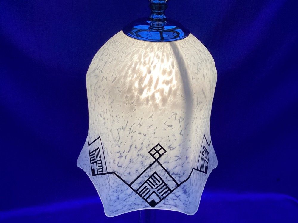 An Art Deco chrome table lamp featuring a central column stem, stepped square base, and a mottled frosted glass bell shade decorated with black geometric diamond motifs. View VI