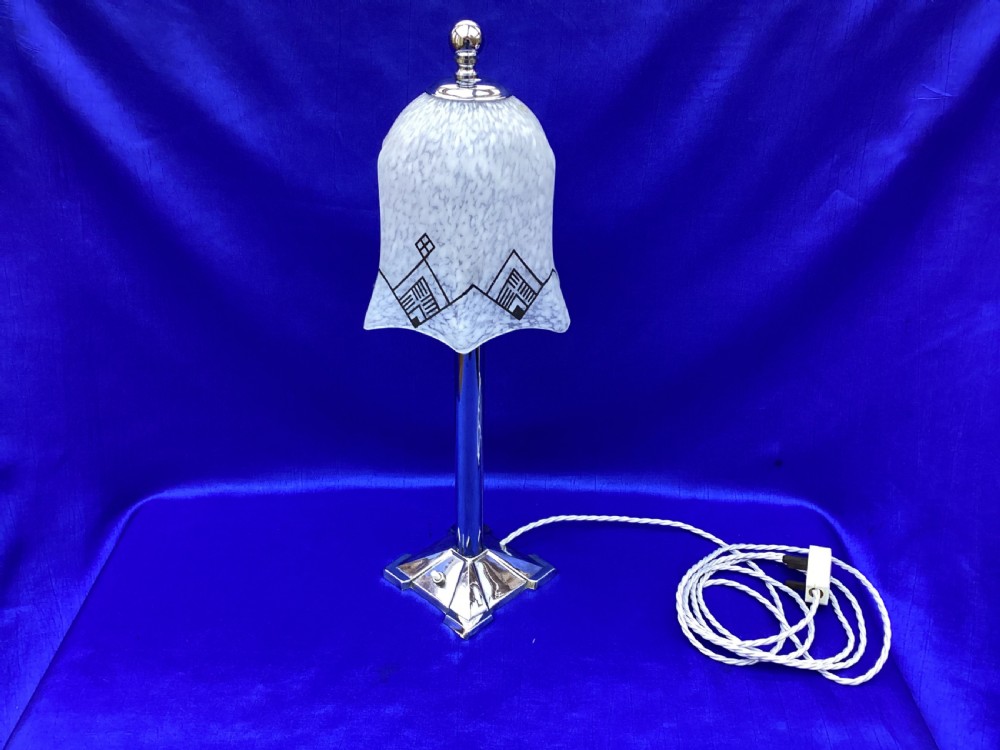 An Art Deco chrome table lamp featuring a central column stem, stepped square base, and a mottled frosted glass bell shade decorated with black geometric diamond motifs. View VIII