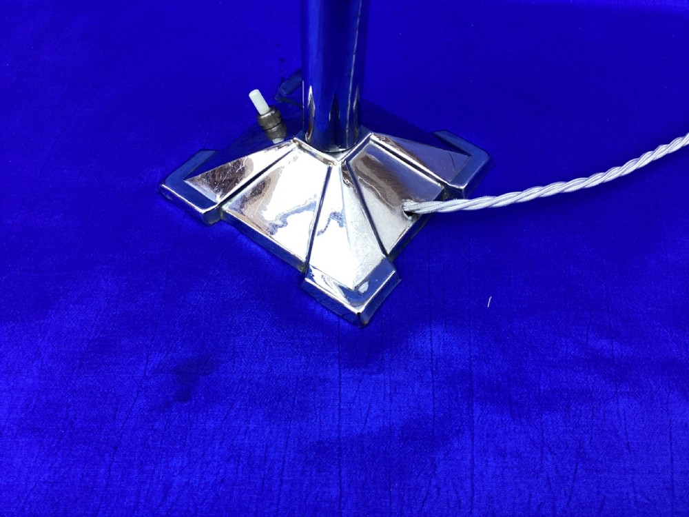 An Art Deco chrome table lamp featuring a central column stem, stepped square base, and a mottled frosted glass bell shade decorated with black geometric diamond motifs. View IX