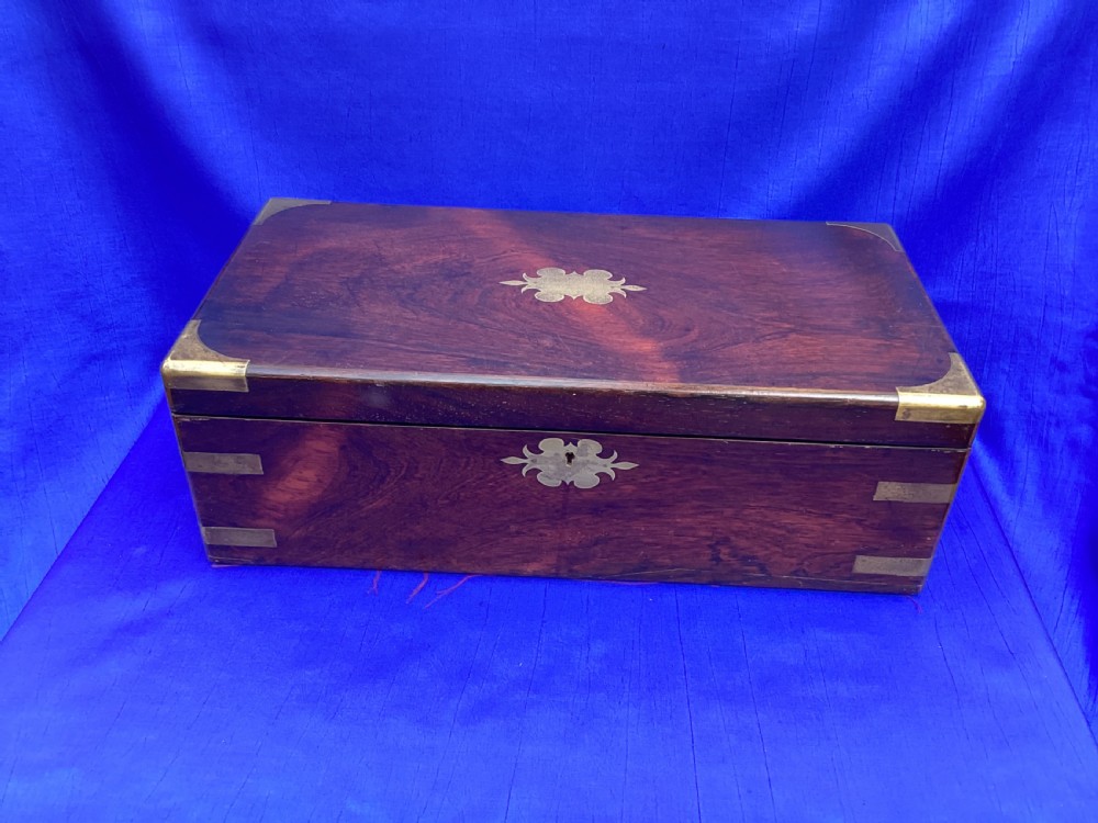 A closed rectangular Georgian rosewood writing slope with polished brass corner mounts and a central brass escutcheon.