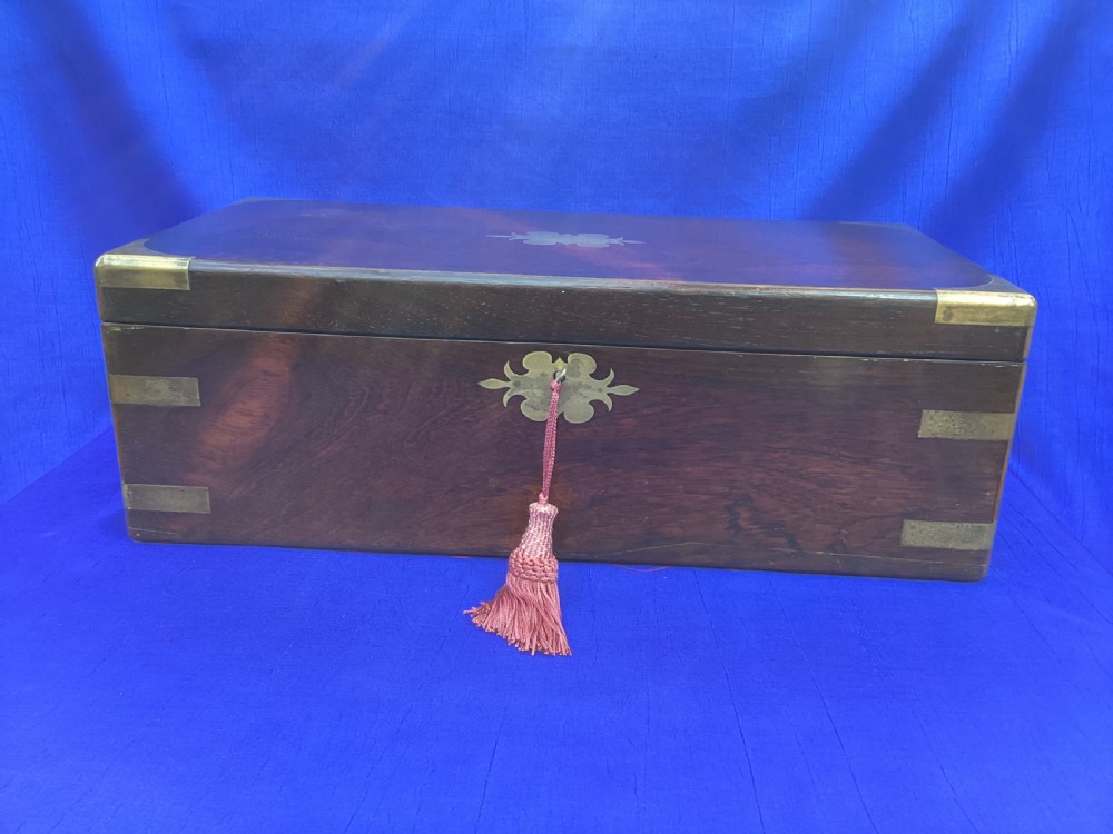 A closed rectangular Georgian rosewood writing slope with polished brass corner mounts and a central brass escutcheon. View II