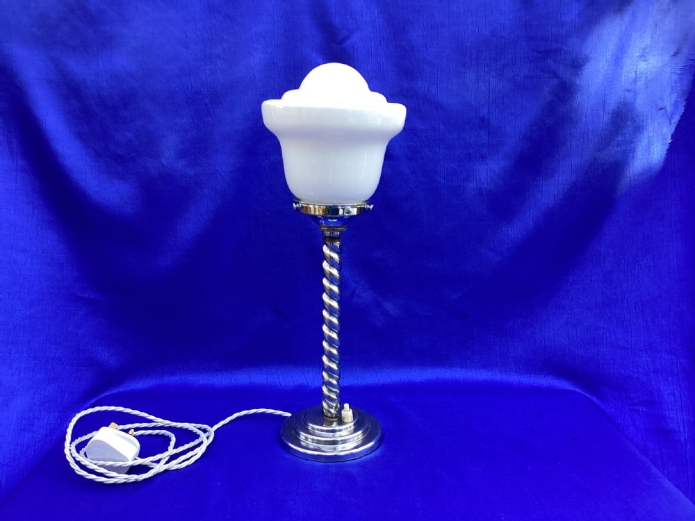 An Art Deco chrome table lamp featuring a twisted spiral stem, a tiered circular base, and a white glass shade.
