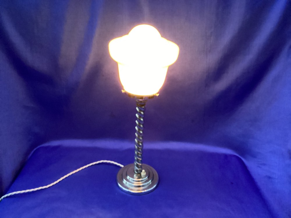 An Art Deco chrome table lamp featuring a twisted spiral stem, a tiered circular base, and a white glass shade. View VII