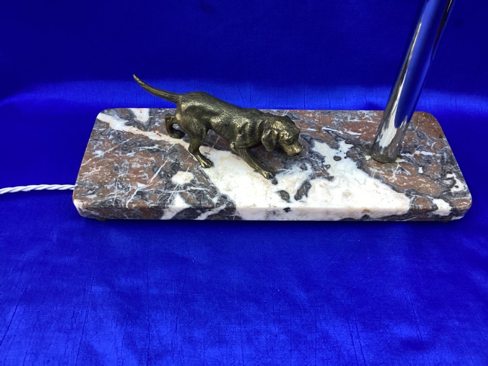 An Art Deco French table lamp featuring a cast brass hound figure mounted on a rectangular veined marble base beside a stem supporting a pale green globe shade. View V