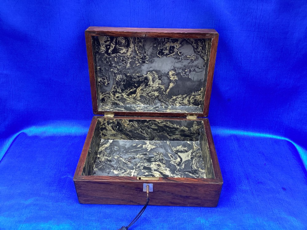 A rectangular dark rosewood trinket box with a mother-of-pearl cartouche on top, a mother-of-pearl keyhole escutcheon, and a brass key with a black tassel. View IV
