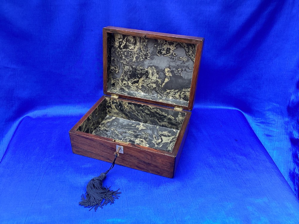 A rectangular dark rosewood trinket box with a mother-of-pearl cartouche on top, a mother-of-pearl keyhole escutcheon, and a brass key with a black tassel. View VI