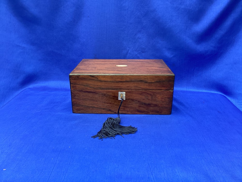 A rectangular dark rosewood trinket box with a mother-of-pearl cartouche on top, a mother-of-pearl keyhole escutcheon, and a brass key with a black tassel. View VII