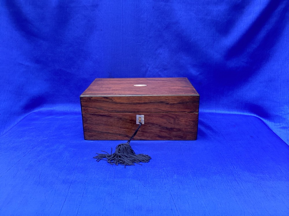 A rectangular dark rosewood trinket box with a mother-of-pearl cartouche on top, a mother-of-pearl keyhole escutcheon, and a brass key with a black tassel. View VIII